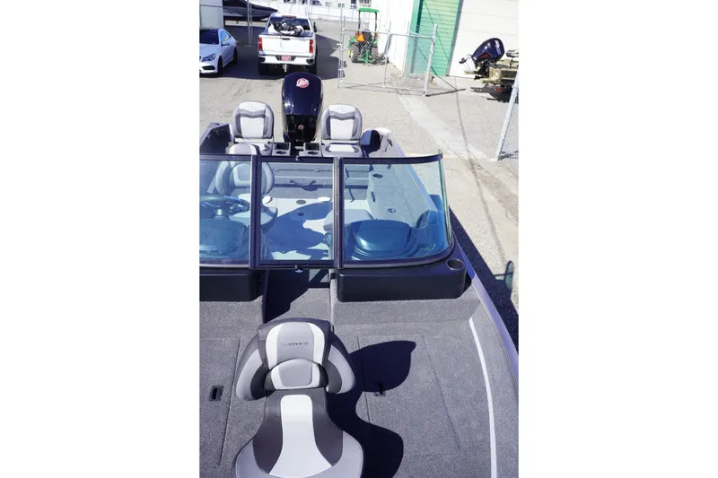 Slide: The Image of 2026 Lowe Fishing Machine 1775WT boat with seating and windshield, parked outdoors. - 14