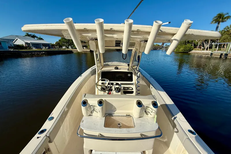 Slide: The Image of 2022 Scout 277 LXF boat on calm water, featuring a spacious deck and rod holders. - 19