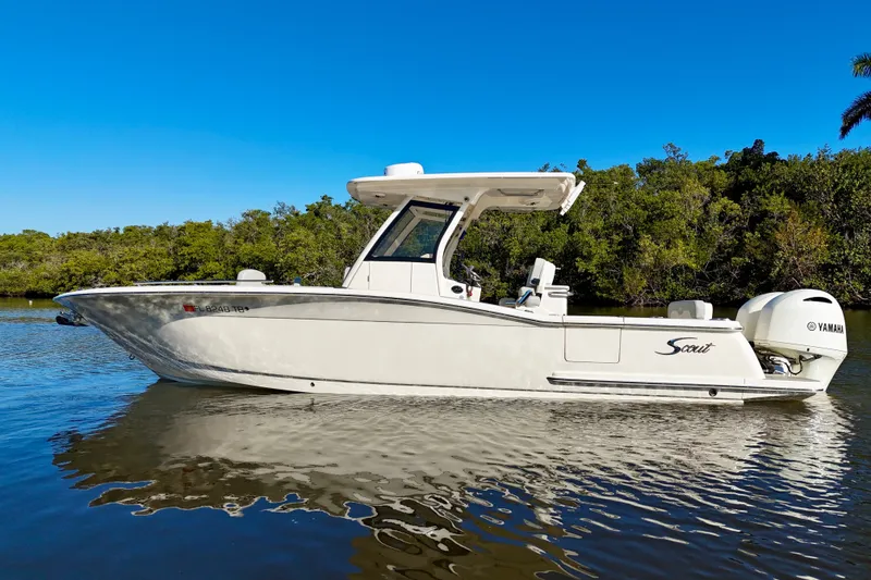 Slide: The Image of 2022 Scout 277 LXF boat on calm water with clear blue sky. - 2
