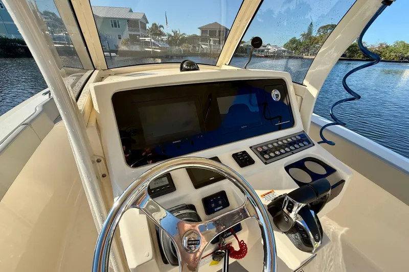 Slide: The Image of 2022 Scout 277 LXF boat dashboard with steering wheel and control panel. - 20