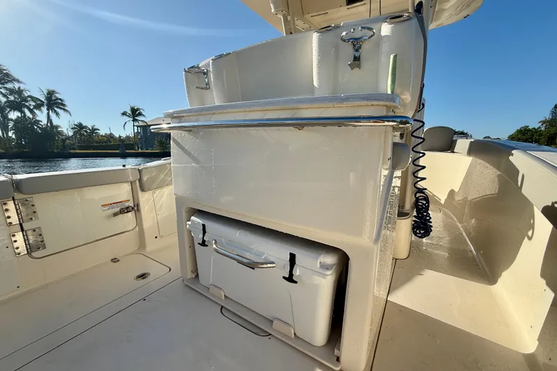 Slide: The Image of 2022 Scout 277 LXF boat interior with storage compartment and cooler, sunny day. - 27
