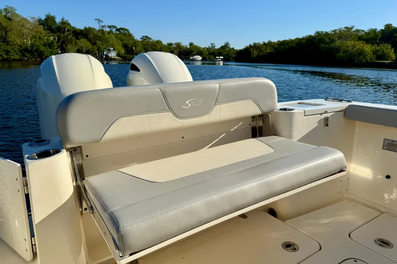 Slide: The Image of 2022 Scout 277 LXF boat with cushioned seating on a serene waterway. - 30