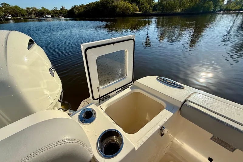 Slide: The Image of 2022 Scout 277 LXF boat with open storage compartment on calm water. - 33