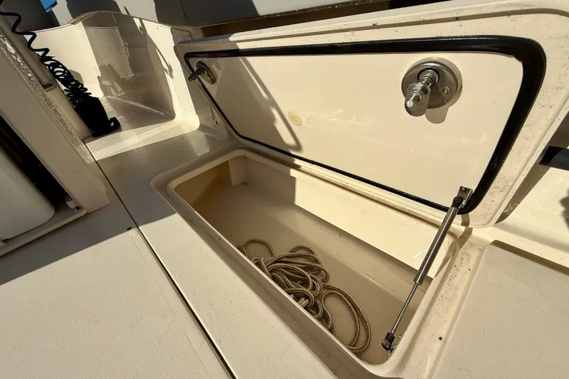 Slide: The Image of Storage compartment on a 2022 Scout 277 LXF boat, featuring a coiled rope inside. - 35