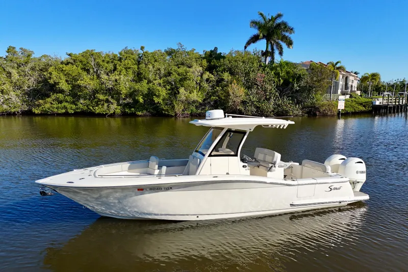 Slide: The Image of 2022 Scout 277 LXF boat on calm water with lush greenery background. - 5