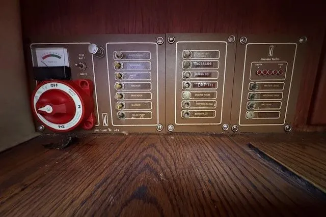 Slide: The Image of 1977 Islander 32 electrical panel with switches and gauges on wooden surface. - 13