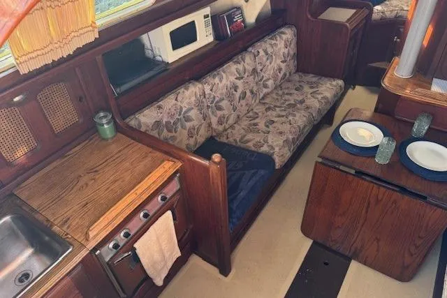 Slide: The Image of 1977 Islander 32 yacht interior with kitchen, floral sofa, and dining area. - 17
