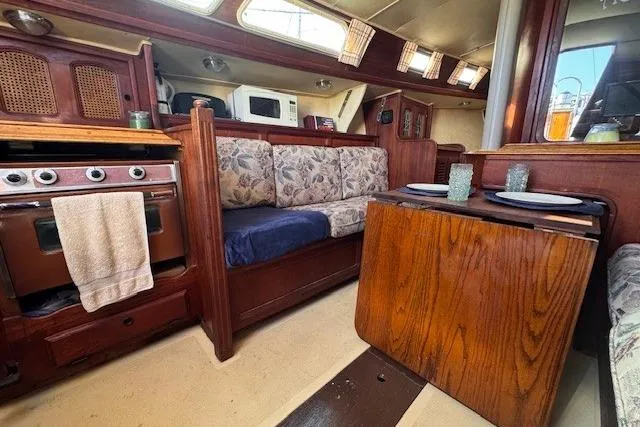 Slide: The Image of 1977 Islander 32 yacht interior with cozy seating, wooden table, and kitchen area. - 19
