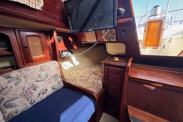 Slide: The Image of 1977 Islander 32 sailboat interior with floral upholstery, wood finish, and mounted TV. - 24