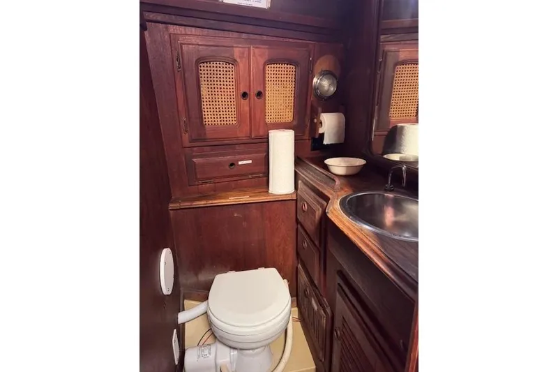 Slide: The Image of 1977 Islander 32 yacht bathroom with wooden cabinets, sink, and toilet. - 25