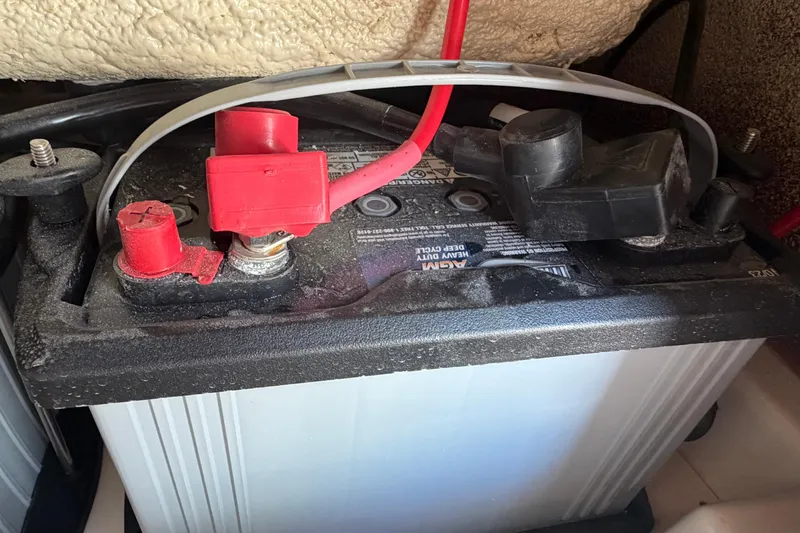 Slide: The Image of Battery compartment of 2024 Grady-White Fisherman 236 boat, featuring red and black terminals. - 58