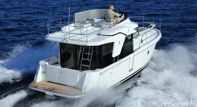 Slide: The Image of Manufacturer Provided Image: 2020 Beneteau Swift Trawler 30 cruising on blue water near rocky shoreline. - 12