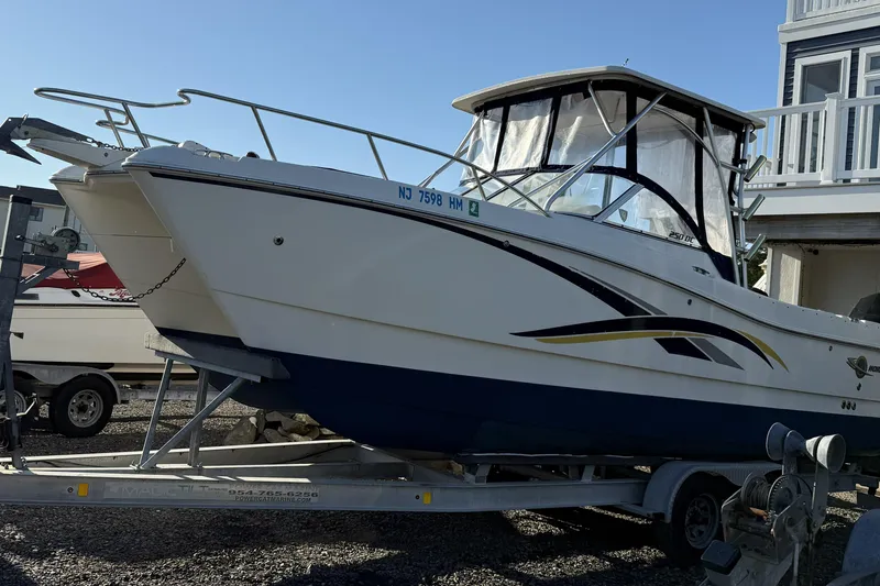 The Image of 2005 World Cat 250 DC boat on trailer, parked outdoors near a building. - 0