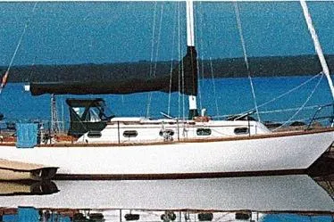 The Image of 1980 Cape Dory 33 sailboat docked on calm water with blue sky background. - 0
