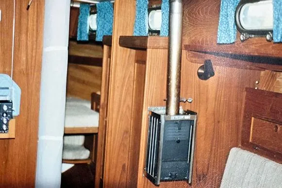 Slide: The Image of Interior of a 1980 Cape Dory 33 sailboat, featuring wood paneling and a compact heater. - 10