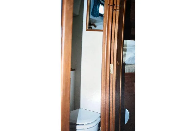 Slide: The Image of Interior view of a 1980 Cape Dory 33 sailboat bathroom with wooden door and compact toilet. - 17