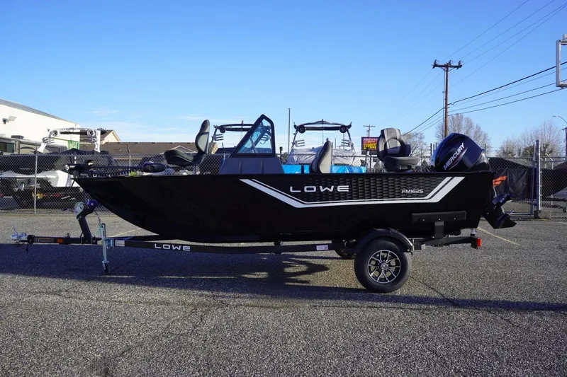 The Image of 2026 Lowe Fishing Machine 1625WT boat on trailer, parked outdoors. - 1