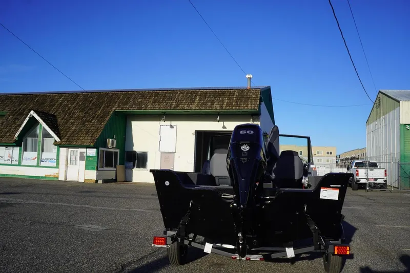 Slide: The Image of 2026 Lowe Fishing Machine 1625WT boat parked outside a green building. - 7