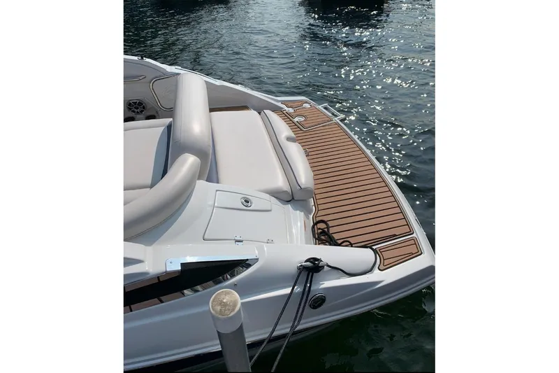 Slide: The Image of 2014 Crownline Eclipse E2 boat with cushioned seating and wooden deck on water. - 2