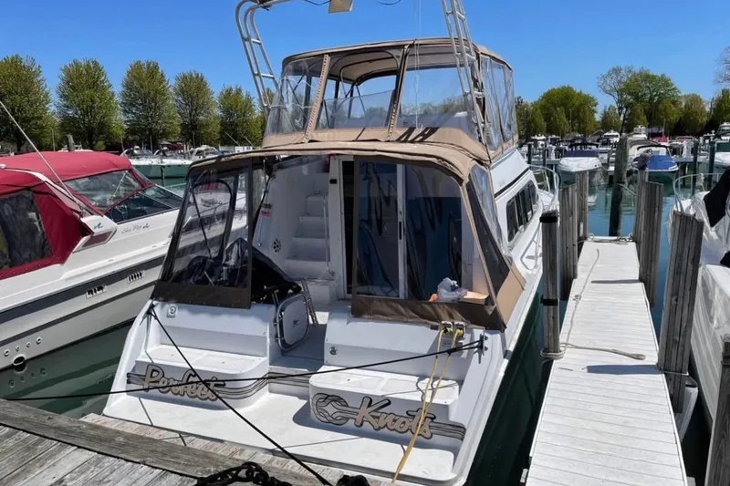 Slide: The Image of 1996 Mainship 40 Sedan Bridge docked at marina, featuring tan canopy and spacious deck. - 4