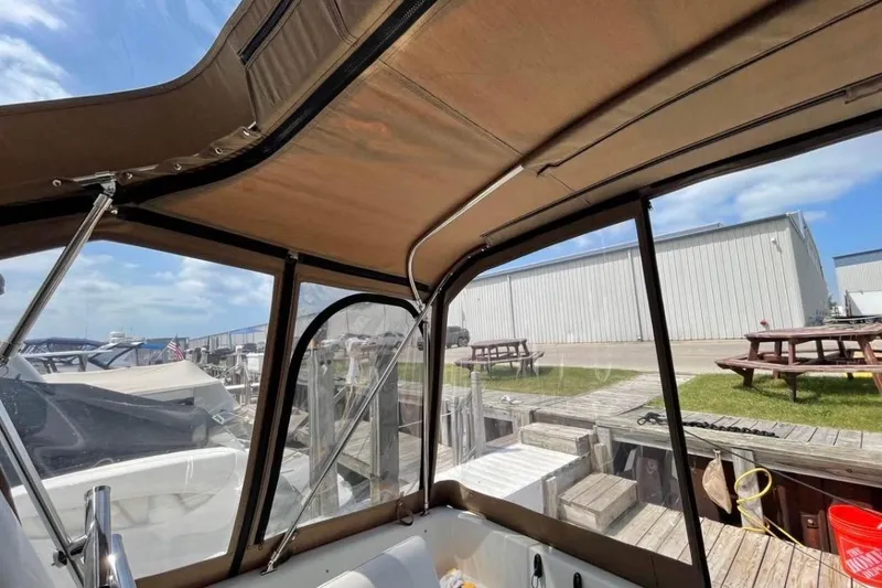 Slide: The Image of 1996 Mainship 40 Sedan Bridge boat interior with canopy, docked at marina under blue sky. - 6