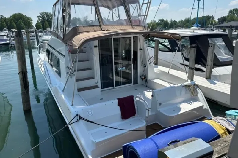 Slide: The Image of 1996 Mainship 40 Sedan Bridge docked at marina, featuring spacious deck and covered bridge. - 7