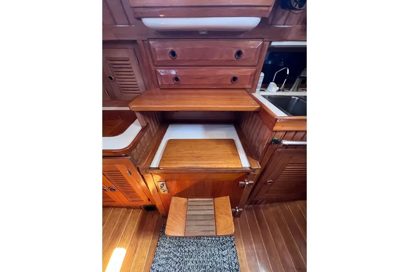 Slide: The Image of Interior of 1990 Cabo Rico 38R sailboat featuring wooden cabinetry and compact kitchen area. - 13