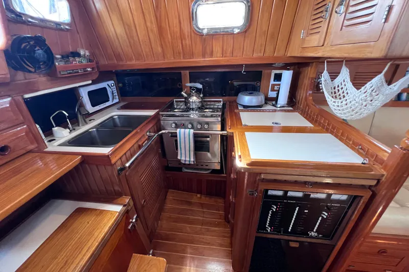 Slide: The Image of Cabo Rico 38R 1990 yacht kitchen with wood cabinetry, stove, and sink. - 32