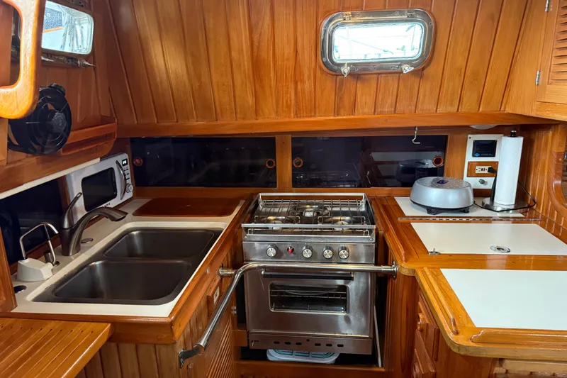 Slide: The Image of Galley kitchen in 1990 Cabo Rico 38R sailboat with wood paneling and stainless steel appliances. - 6