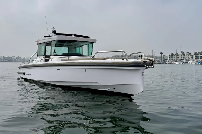 Slide: The Image of 2023 Axopar 28 Cabin boat on calm water, overcast sky background. - 10