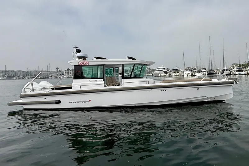 Slide: The Image of 2023 Axopar 28 Cabin boat on calm water, docked in a marina. - 11