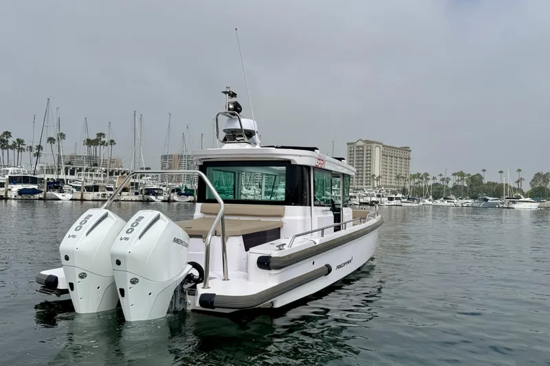 Slide: The Image of 2023 Axopar 28 Cabin boat with twin Mercury engines in a marina setting. - 12