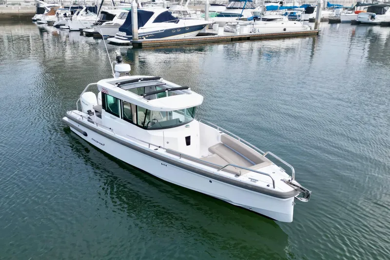 Slide: The Image of 2023 Axopar 28 Cabin boat docked in a marina, surrounded by other vessels. - 14