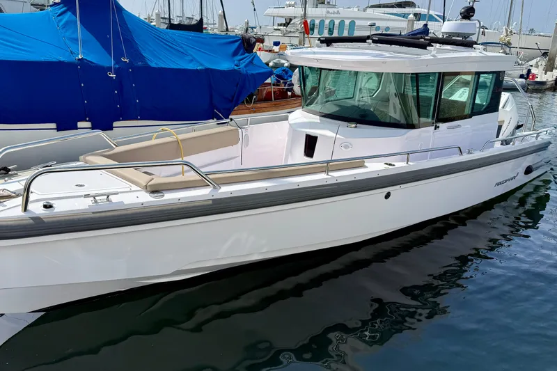 Slide: The Image of 2023 Axopar 28 Cabin boat docked in a marina, featuring sleek design and modern amenities. - 18