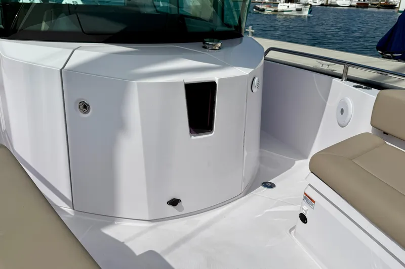 Slide: The Image of 2023 Axopar 28 Cabin boat interior with seating and sleek design at a marina. - 20
