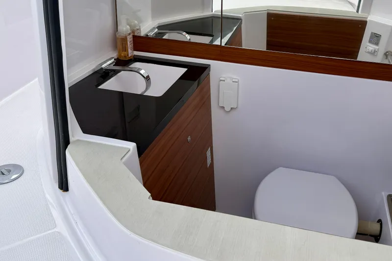 Slide: The Image of 2023 Axopar 28 Cabin bathroom with modern sink and toilet, featuring wood accents. - 21