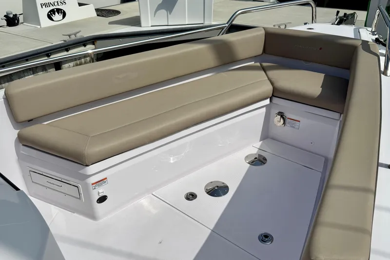 Slide: The Image of 2023 Axopar 28 Cabin boat seating area with beige cushions and storage compartments. - 22