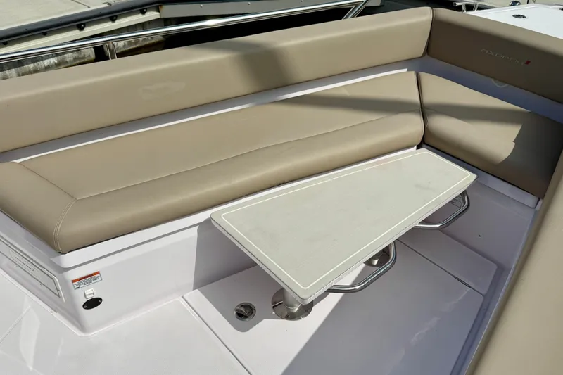 Slide: The Image of 2023 Axopar 28 Cabin boat interior with beige seating and a compact table. - 23