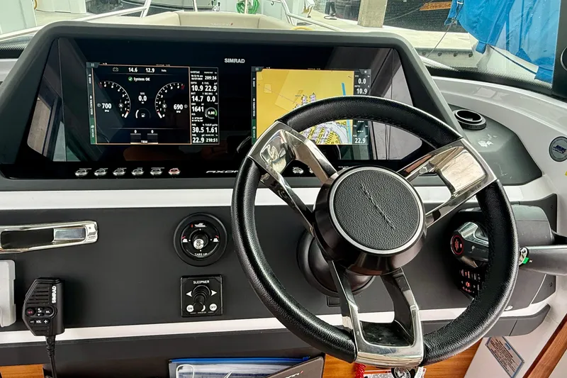 Slide: The Image of Steering wheel and dashboard of 2023 Axopar 28 Cabin boat with navigation displays. - 32