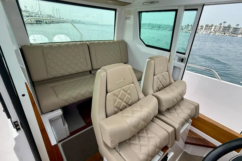 Slide: The Image of 2023 Axopar 28 Cabin interior with luxurious beige seating and ocean view. - 38