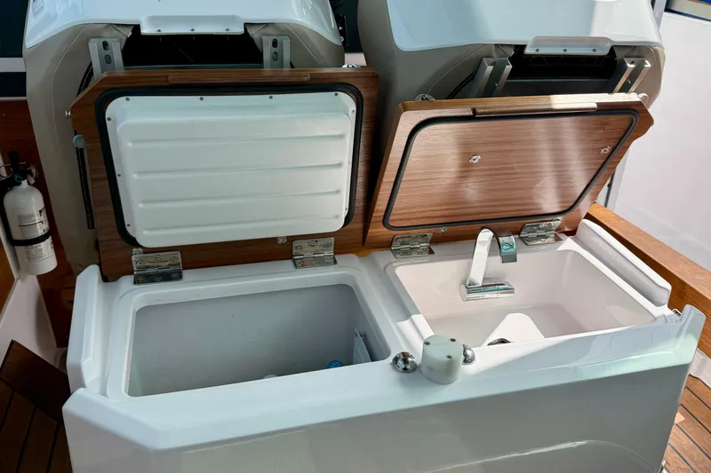 Slide: The Image of 2023 Axopar 28 Cabin boat interior with open storage compartments and sink. - 42