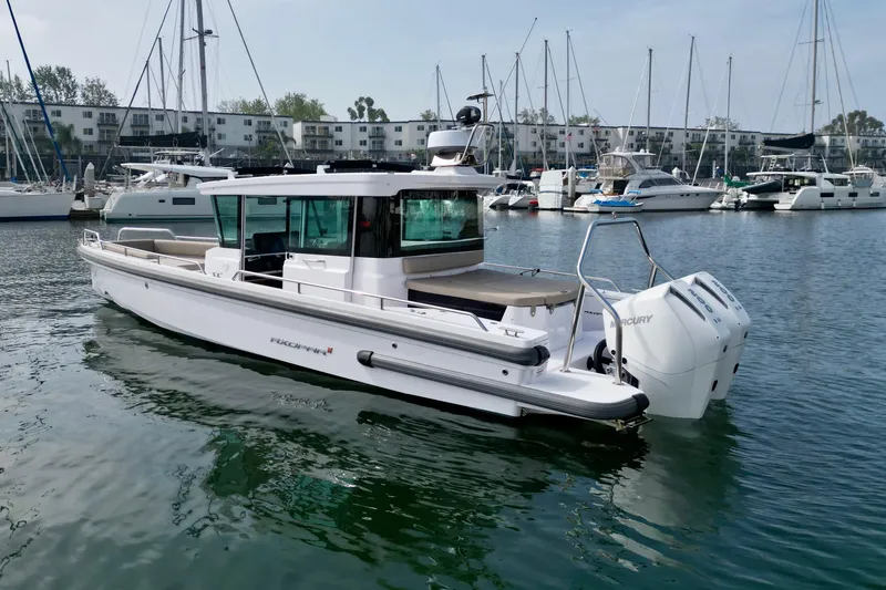 Slide: The Image of 2023 Axopar 28 Cabin boat docked in a marina, surrounded by sailboats. - 5