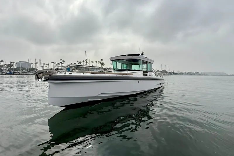 Slide: The Image of 2023 Axopar 28 Cabin boat on calm water with cloudy sky backdrop. - 9