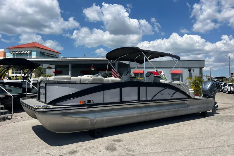 The Image of 2017 Sylvan Mandalay 8525 Sportlounger Twin pontoon boat parked outdoors under a blue sky. - 1