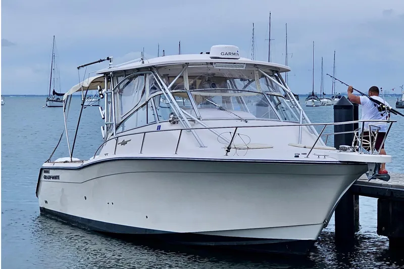 Slide: The Image of 2006 Grady-White Express 330 boat docked, with fishing rods and calm sea background. - 16