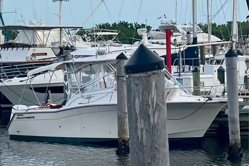 Slide: The Image of 2006 Grady-White Express 330 boat docked at a marina, surrounded by other vessels. - 7