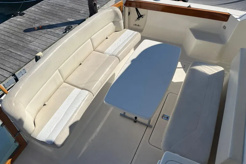 Slide: The Image of 1996 Tiara Yachts 3500 Express interior with beige seating and white table on deck. - 14