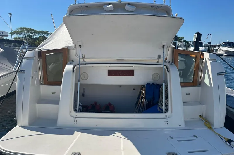 Slide: The Image of 1996 Tiara Yachts 3500 Express boat with open storage compartment at marina dock. - 4