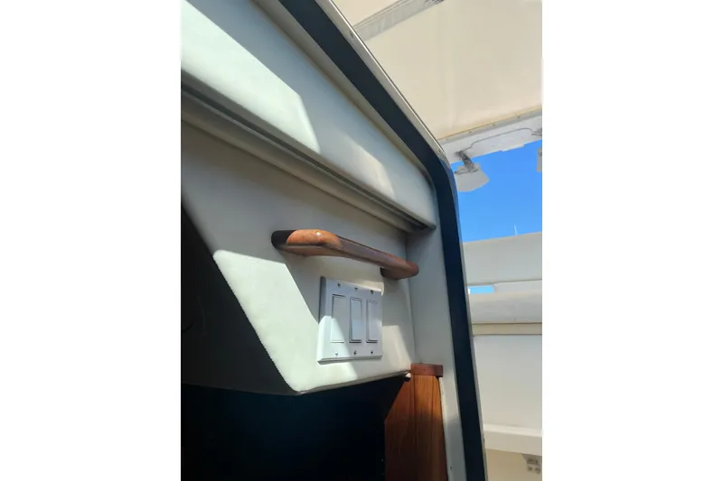 Slide: The Image of Interior view of a 1996 Tiara Yachts 3500 Express, featuring a wooden handrail and light switches. - 48