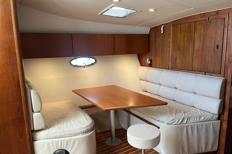 Slide: The Image of Interior of 1996 Tiara Yachts 3500 Express, featuring a cozy dining area with wood accents. - 67